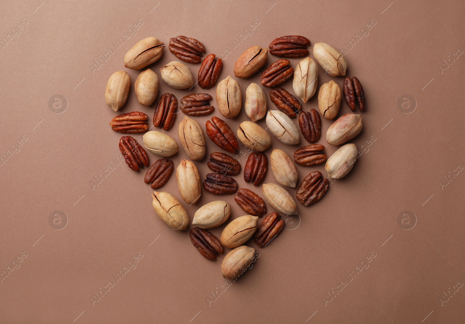 Photo of Heart shape made of pecan nuts on color background, flat lay