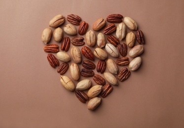 Heart shape made of pecan nuts on color background, flat lay