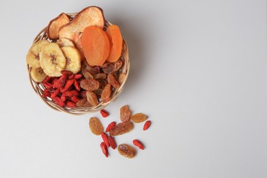 Photo of Wicker basket with different dried fruits on white background, top view. Space for text