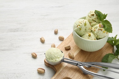 Photo of Tasty pistachio ice cream served on white wooden table, space for text
