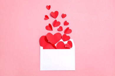 Photo of Envelope with small paper hearts on color background, top view