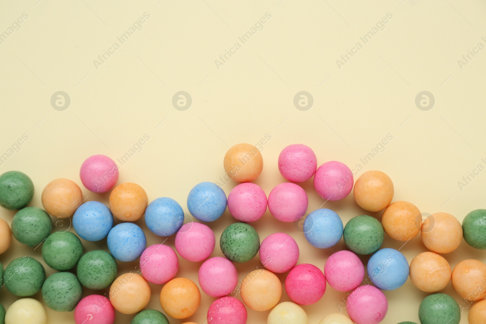 Photo of Many bright chewy gumballs on beige background, flat lay. Space for text