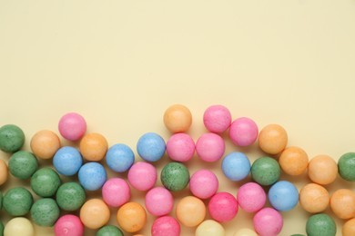 Photo of Many bright chewy gumballs on beige background, flat lay. Space for text