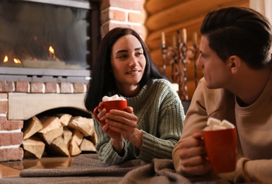 Lovely couple with sweet cocoa near fireplace indoors