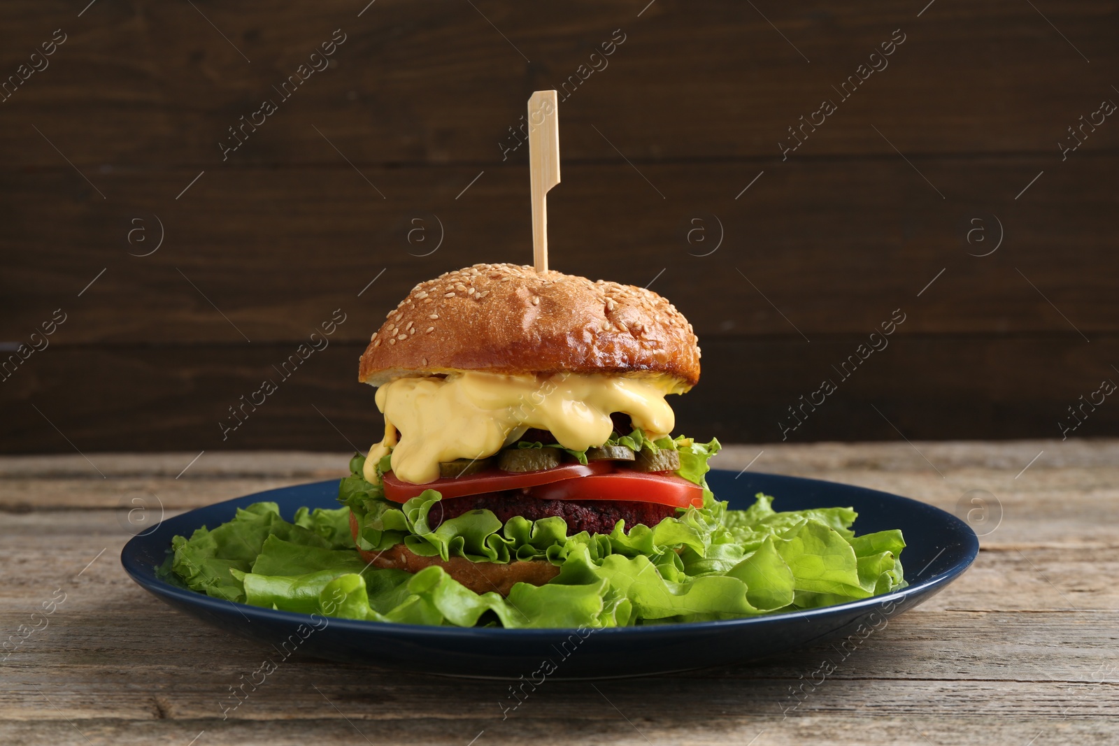 Photo of Delicious vegetarian burger served on wooden table