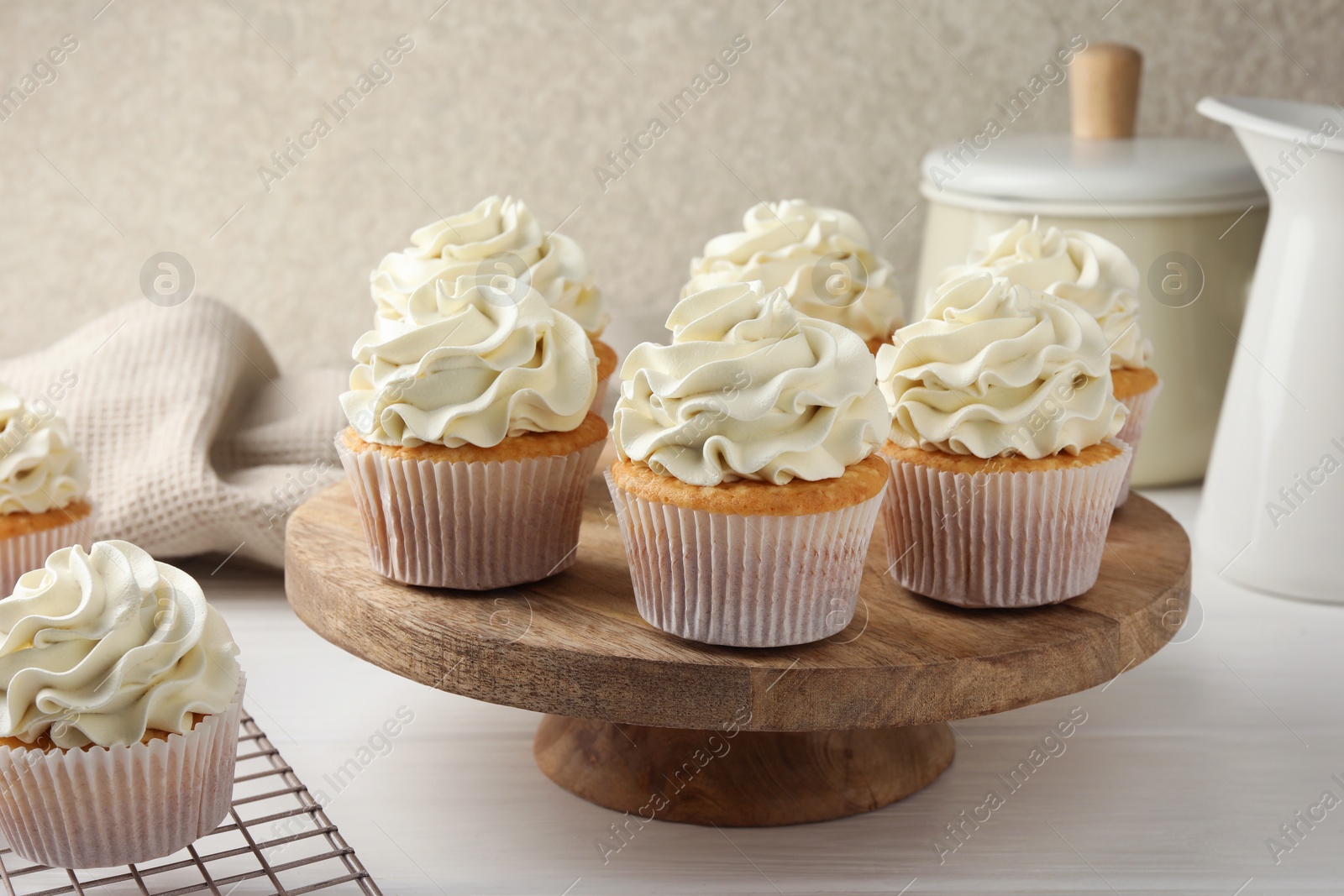 Photo of Tasty vanilla cupcakes with cream on white wooden table