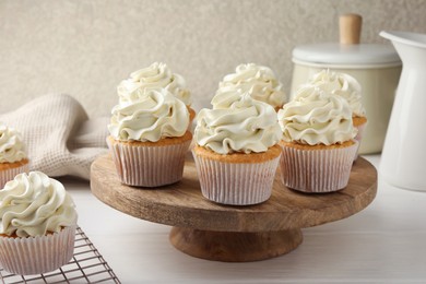 Photo of Tasty vanilla cupcakes with cream on white wooden table