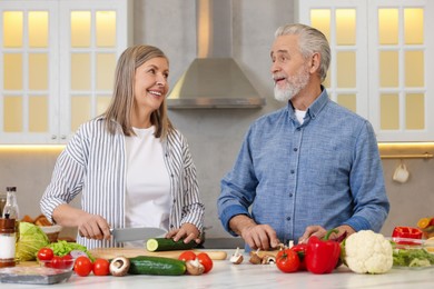 Happy senior couple cooking together in kitchen