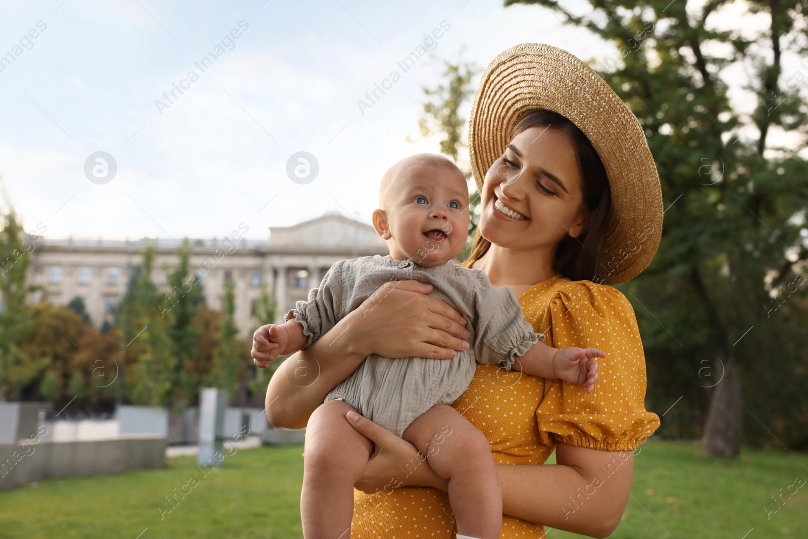 Photo of Happy mother with adorable baby walking in park on sunny day, space for text