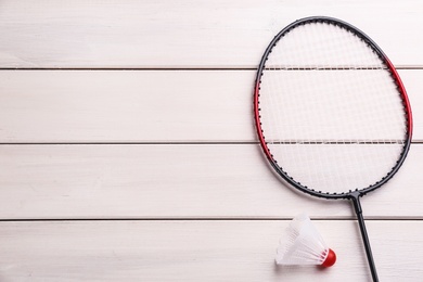 Photo of Badminton racket and shuttlecock on white wooden table, flat lay. Space for text