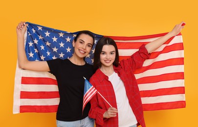 Photo of 4th of July - Independence Day of USA. Happy woman and her daughter with American flags on yellow background