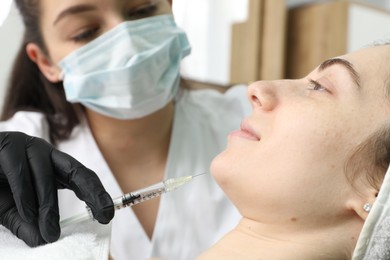 Photo of Cosmetologist giving facial injection to patient in clinic, selective focus. Cosmetic surgery