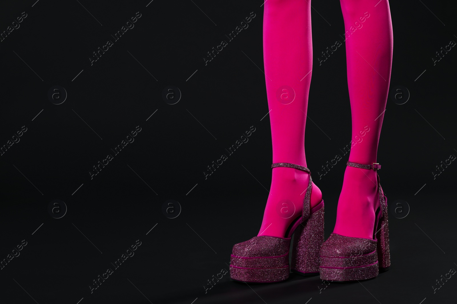 Photo of Woman wearing pink tights and high heeled shoes with platform and square toes on black background, closeup. Space for text