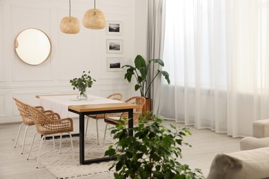 Stylish dining room with cozy furniture, mirror and plants