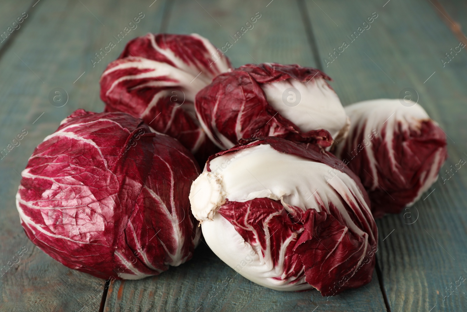 Photo of Whole fresh ripe radicchios on blue wooden table