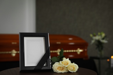Black photo frame and white roses on table in funeral home