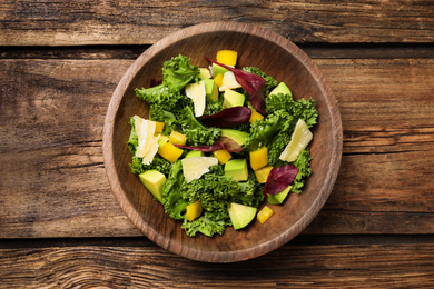 Photo of Delicious kale salad served on wooden table, top view