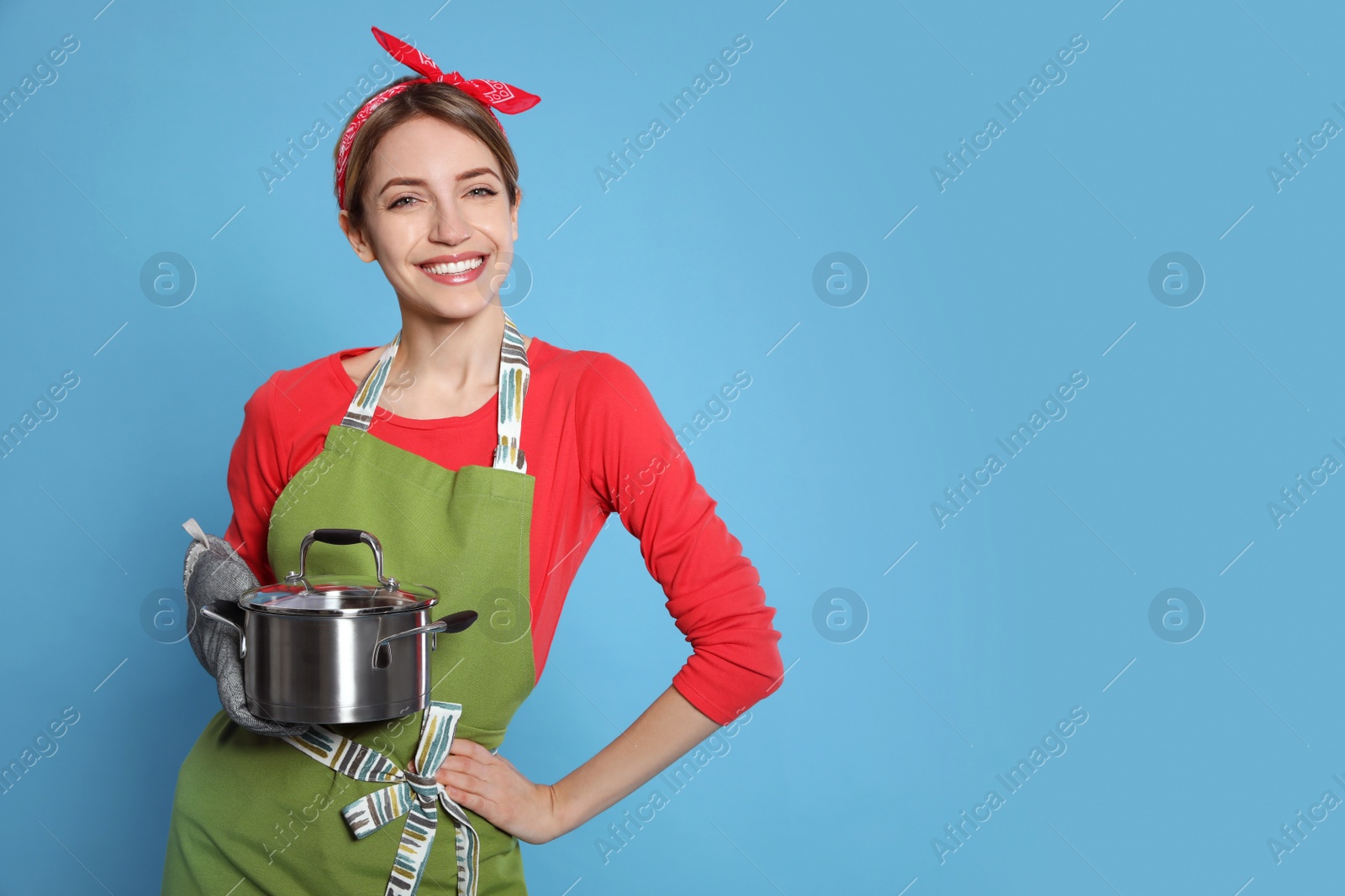 Photo of Young housewife with pot on light blue background. Space for text