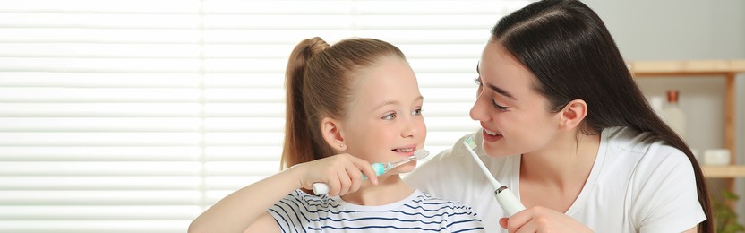 Image of Mother and her daughter brushing teeth together in bathroom. Banner design with space for text