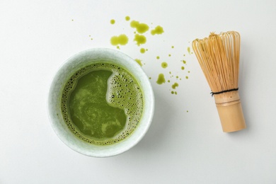 Cup with fresh matcha tea and chasen on light background, top view
