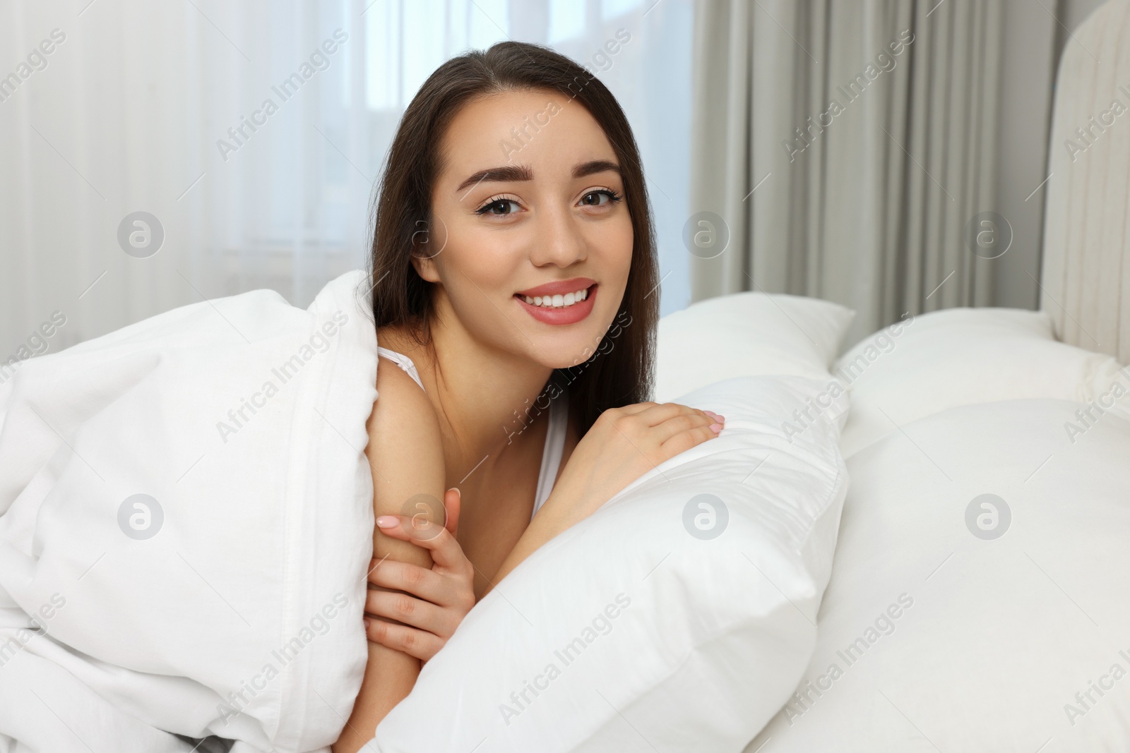 Photo of Beautiful young woman lying in bed at home