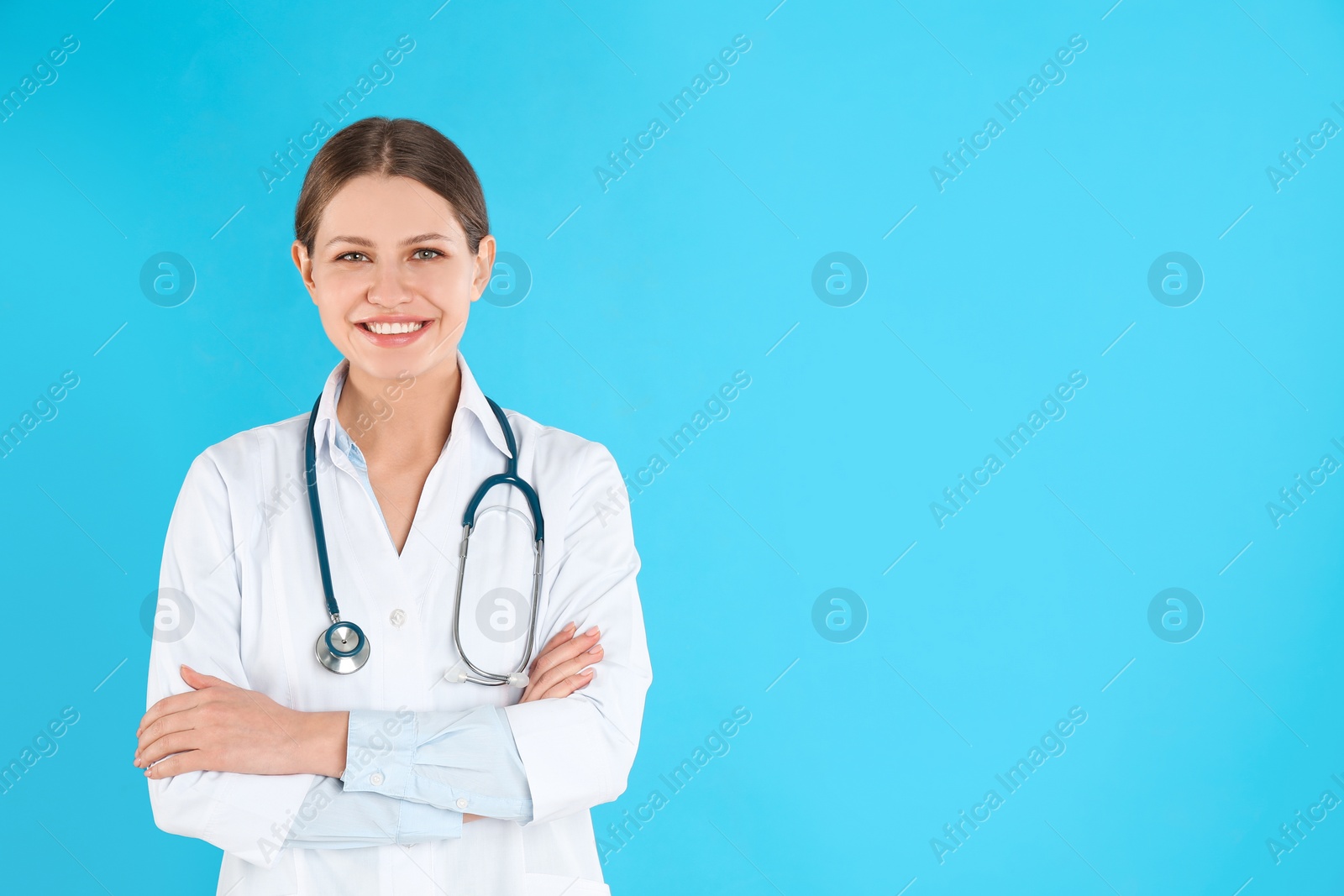 Photo of Portrait of young doctor with stethoscope on blue background, space for text