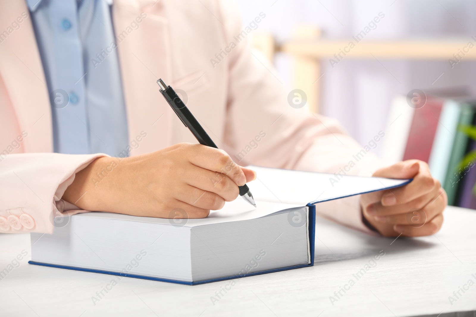 Photo of Writer signing autograph in book at table, closeup