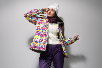 Woman wearing stylish winter sport clothes on light grey background