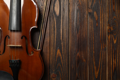 Photo of Classic violin and bow on wooden background, top view. Space for text