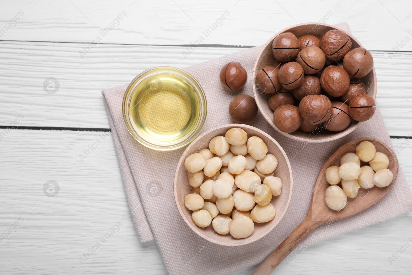 Photo of Delicious organic Macadamia nuts and natural oil on white wooden table, top view. Space for text