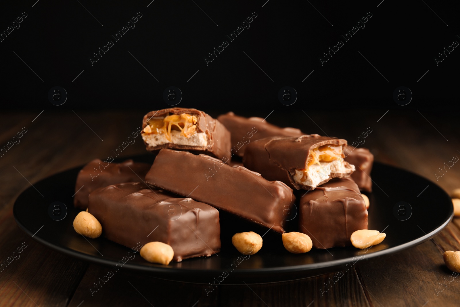 Photo of Plate of chocolate bars with caramel, nuts and nougat on table