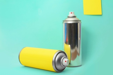 Photo of Cans of different spray paints on color background. Space for text