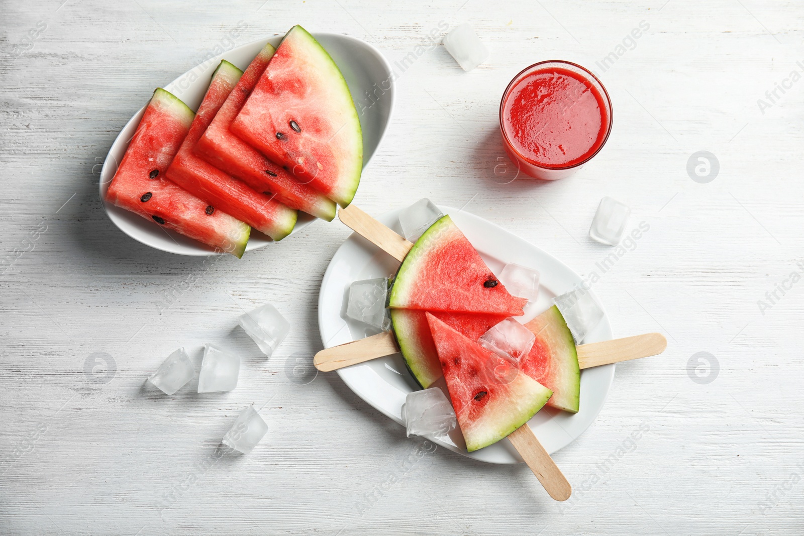 Photo of Flat lay composition with watermelon popsicles and ice cubes on white wooden background