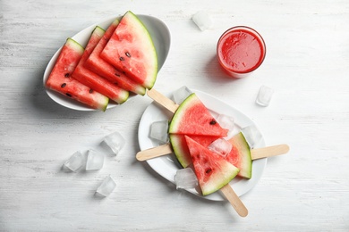 Photo of Flat lay composition with watermelon popsicles and ice cubes on white wooden background