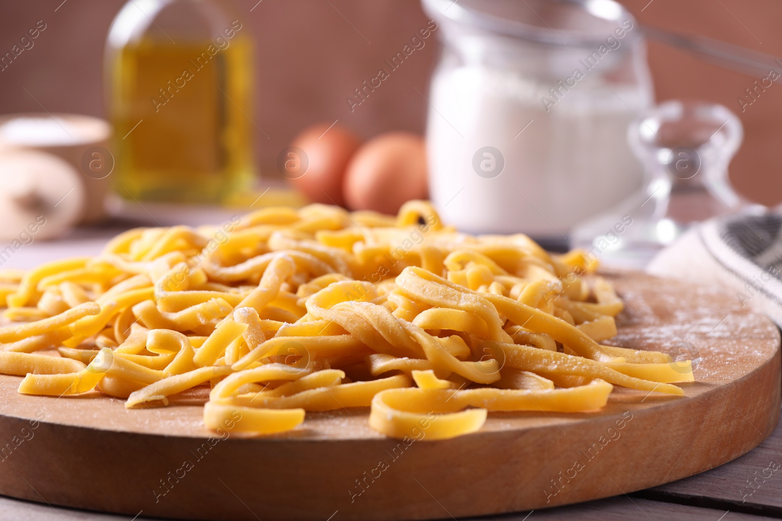 Photo of Board with homemade pasta on wooden table, closeup