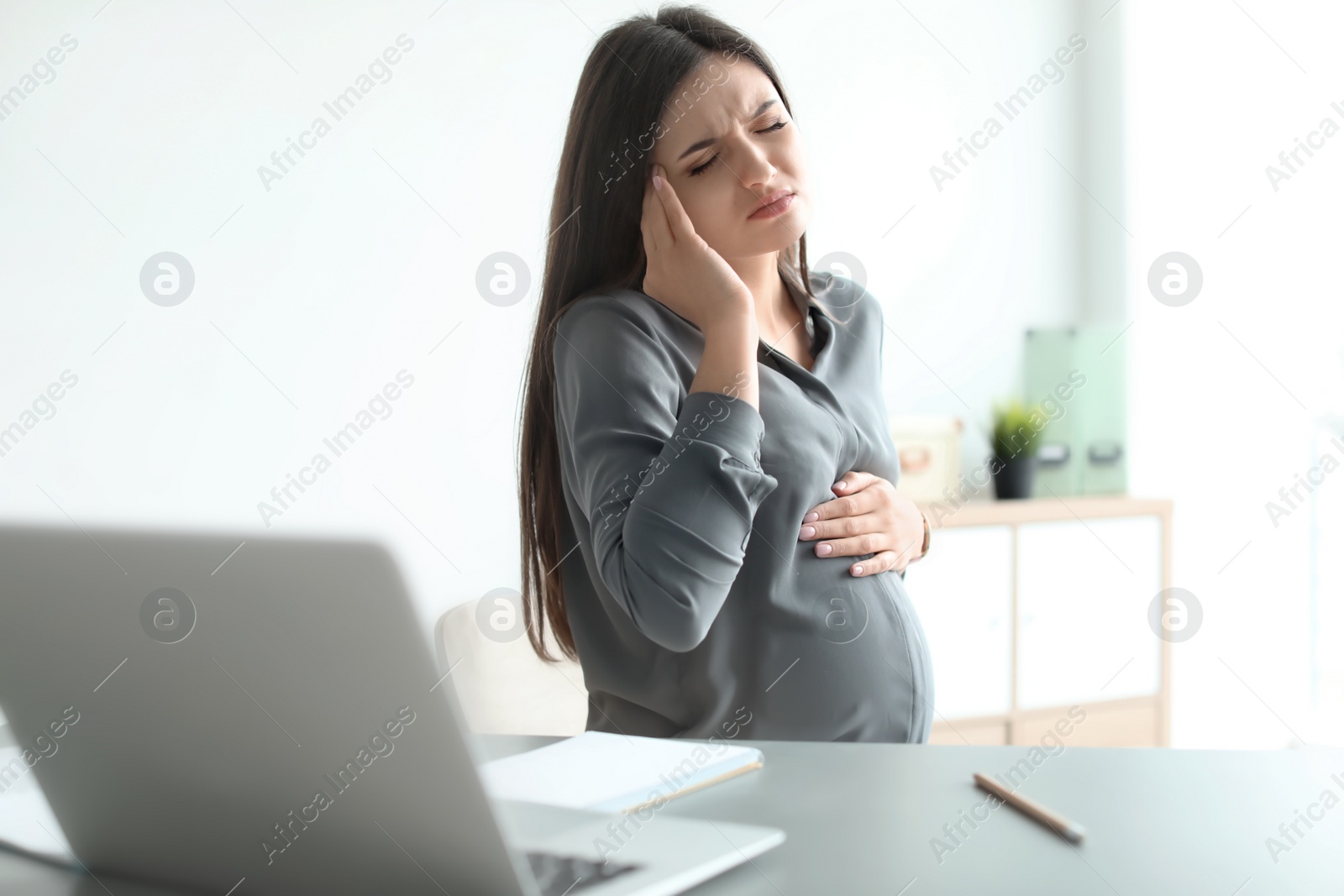 Photo of Pregnant woman suffering from headache at workplace