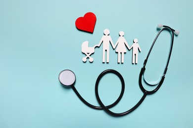 Photo of Figures of family near stethoscope and heart on light blue background, flat lay. Insurance concept