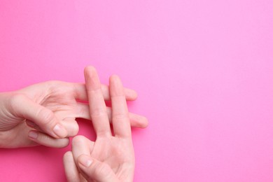 Woman making hashtag symbol with her hands on pink background, top view. Space for text