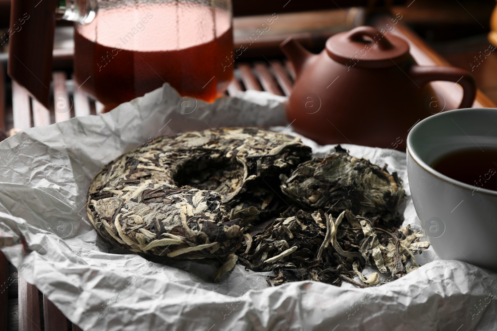 Photo of Broken disc shaped pu-erh tea on parchment paper, closeup. Traditional ceremony