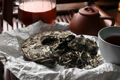 Broken disc shaped pu-erh tea on parchment paper, closeup. Traditional ceremony