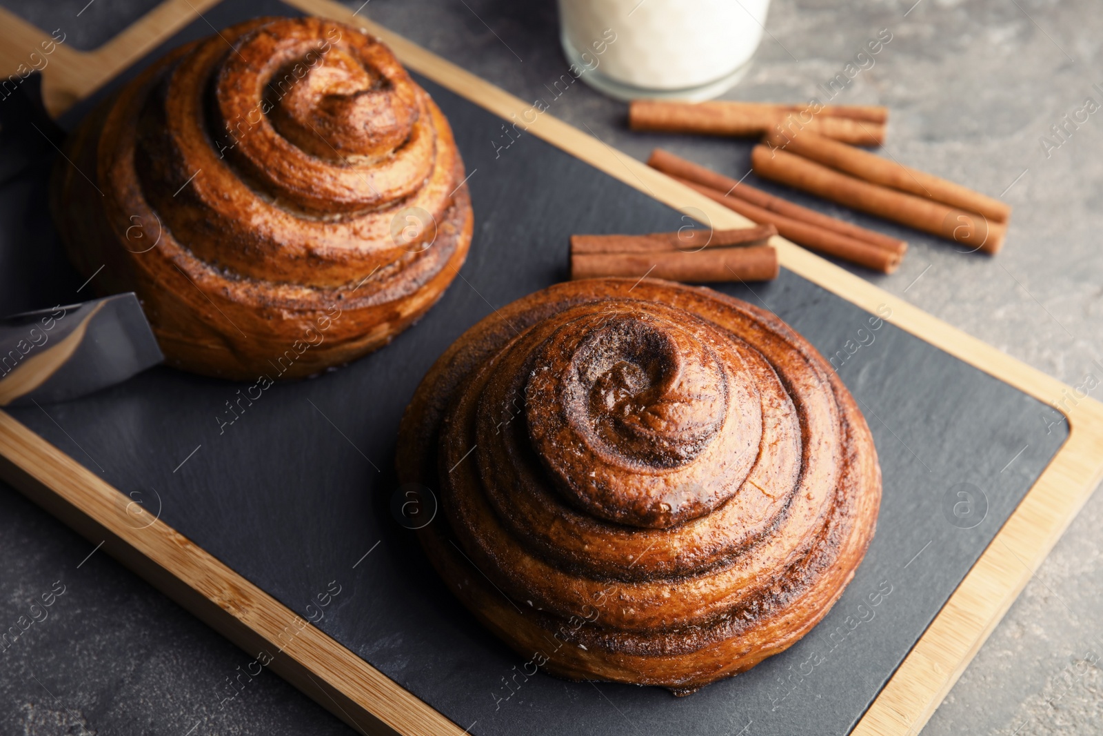 Photo of Board with baked cinnamon rolls on table