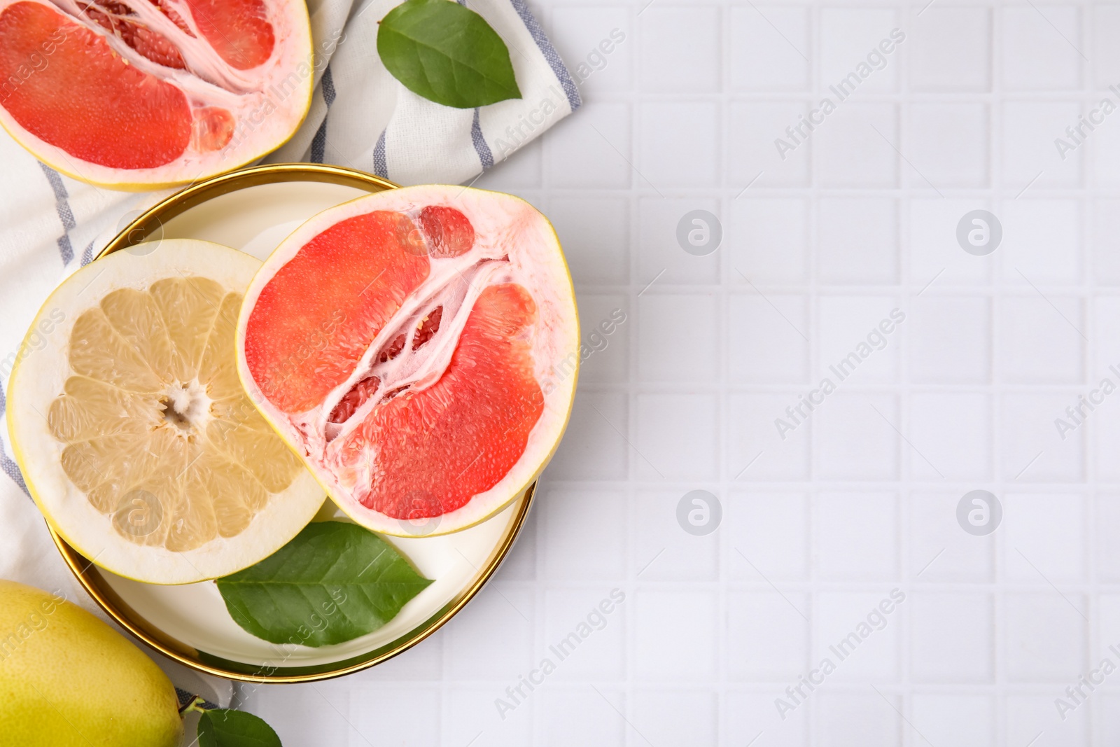 Photo of Different tasty pomelo fruits on white tiled table, flat lay. Space for text
