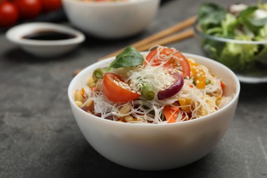 Tasty cooked rice noodles with vegetables on grey table