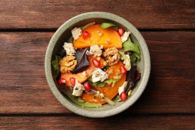 Photo of Delicious persimmon salad with cheese and pomegranate on wooden table, top view