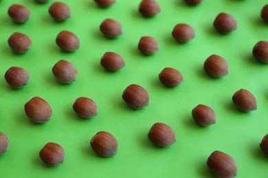 Photo of Brown tasty hazelnuts on green background, closeup