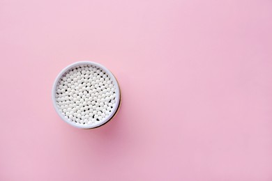 Photo of Container with new cotton buds on pink background, top view. Space for text