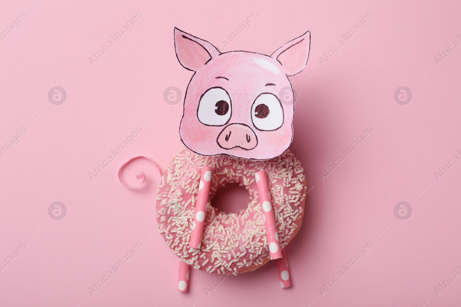 Photo of Funny pig made with donut and piece of paper on pink background, top view