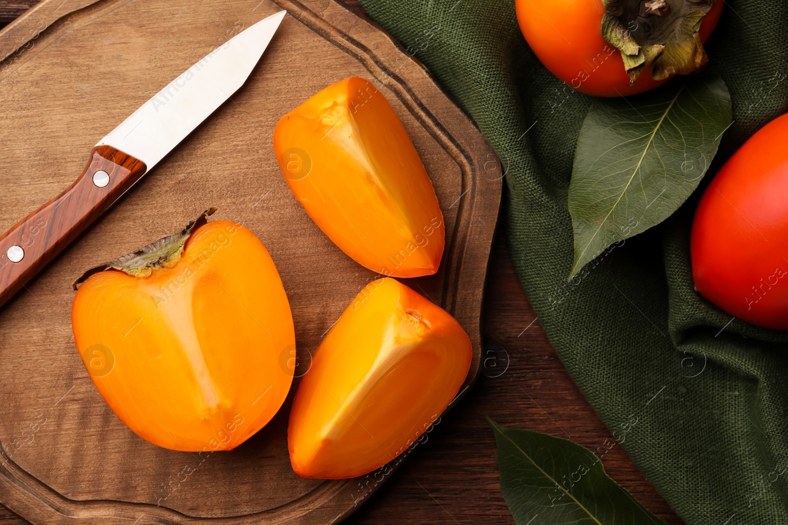 Photo of Delicious ripe persimmons and knife on wooden table, flat lay