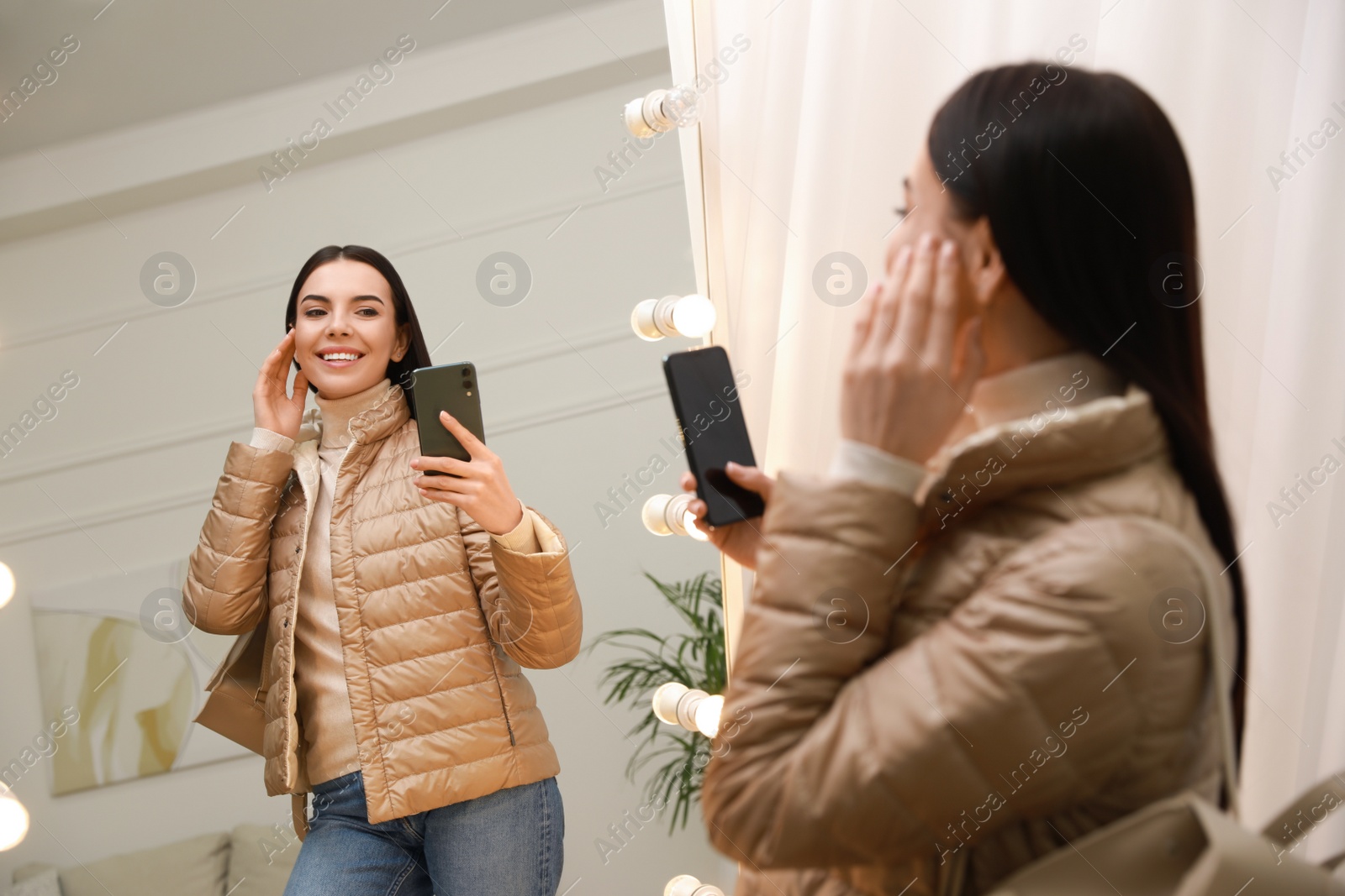 Photo of Young woman taking mirror selfie in stylish outfit at home. Morning routine