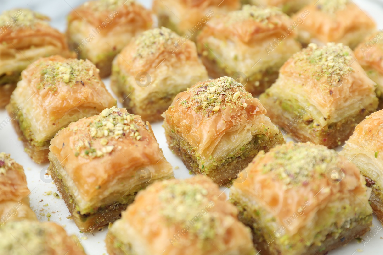 Photo of Delicious fresh baklava with chopped nuts on white table, closeup. Eastern sweets